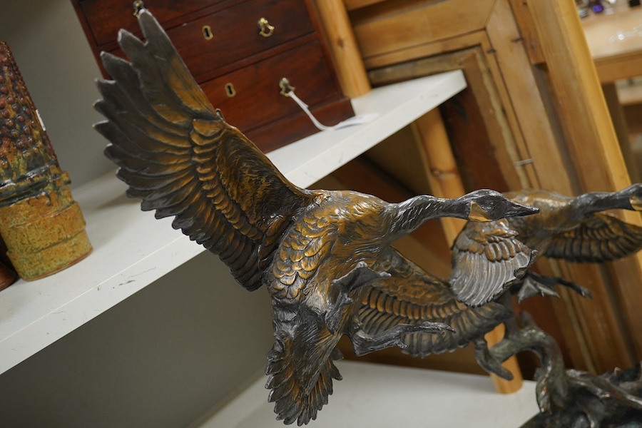 A modern large cast bronze sculpture of two flying geese, on an oval plinth, 90cm wide. Condition - good